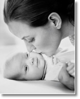 mother kissing newborn baby on cheek